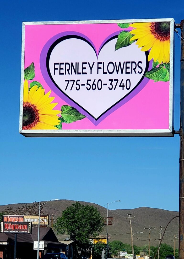 A large sign for fernley flowers on the side of a road.